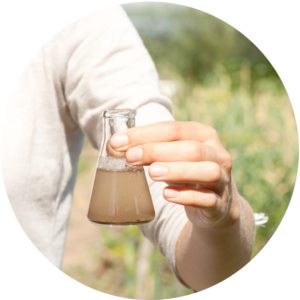 Microbiologist in the field holding a flask full of liquid